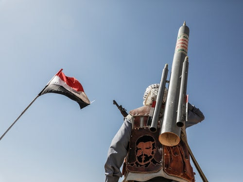 عکس پرچم یمن و فردی با سلاح از پشت.